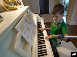 Braden Scott uses a device to support his left arm as he practices on the piano in Tomball, Texas, March 29, 2019.