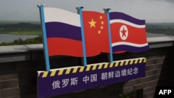 ILUSTRASI - Bendera Rusia (kiri), China (Tengah) dan Korea Utara (kanan) di menara pengamat di perbatasan antara tiga negara di Hunchun, provinsi Jilin di timur laut China, 25 Juni 2015. (GREG BAKER / AFP)