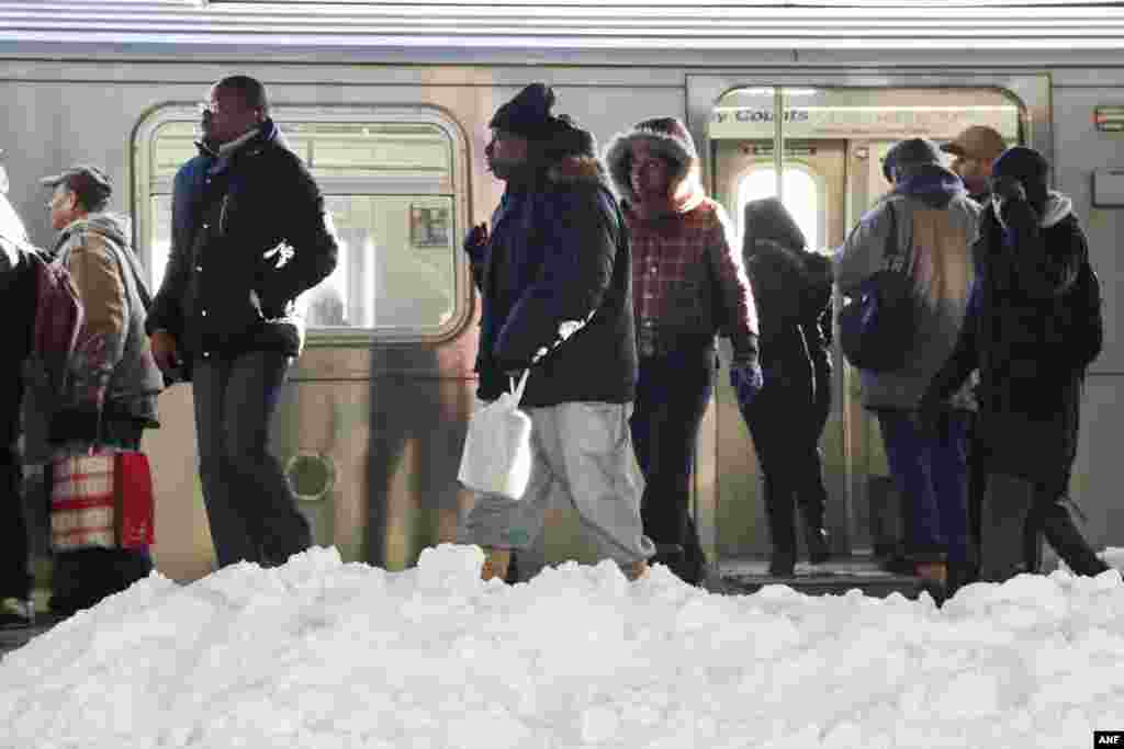 Commuters walk past piles of snow in the elevated Broadway Junction subway station, Monday, Jan. 25, 2016, in the Brooklyn borough of New York. (AP Photo/Mark Lennihan)