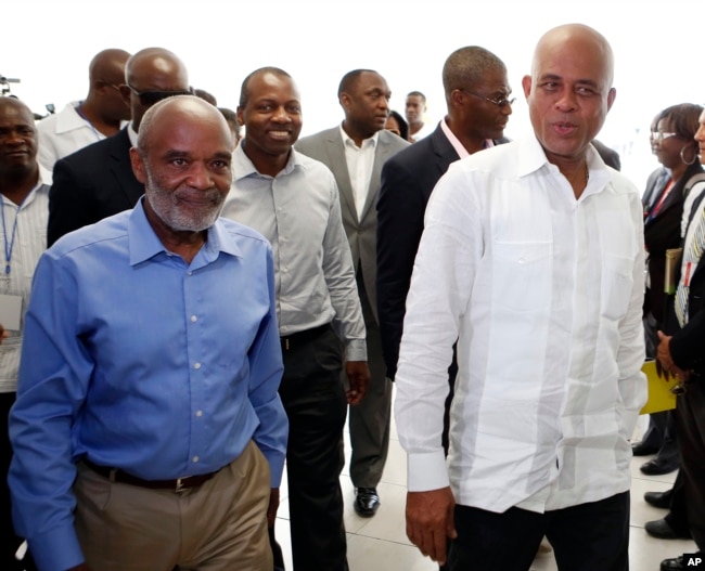 FILE - Haitian President Michel Martelly, right, walks with former Haitian President Rene Preval towards an investors luncheon before the grand opening cermony of the new Caracol Industrial Park in Caracol, Haiti.