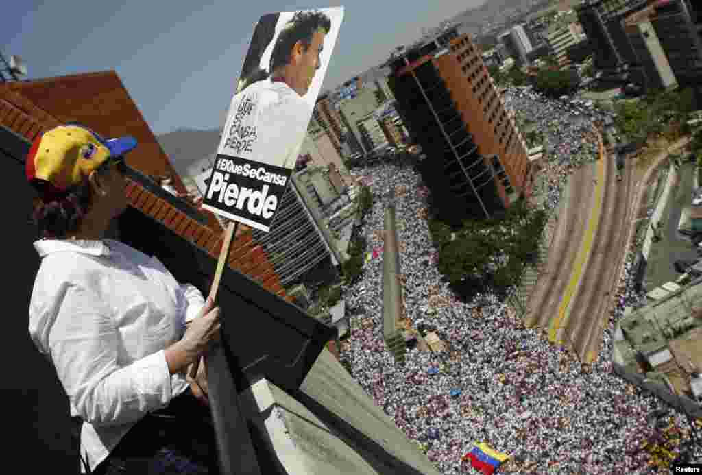 Una opositora observa la marcha con un cartel de Leopoldo López, el líder opositor encarcelado. "El que se cansa, pierde", recuerda el rótulo.