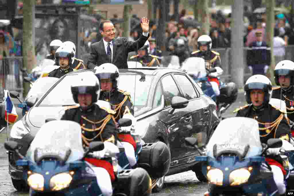 Francois Hollande waves from his car as he drives down the Champs Elysees avenue after the handover ceremony with outgoing French President Nicolas Sarkozy. (AP)