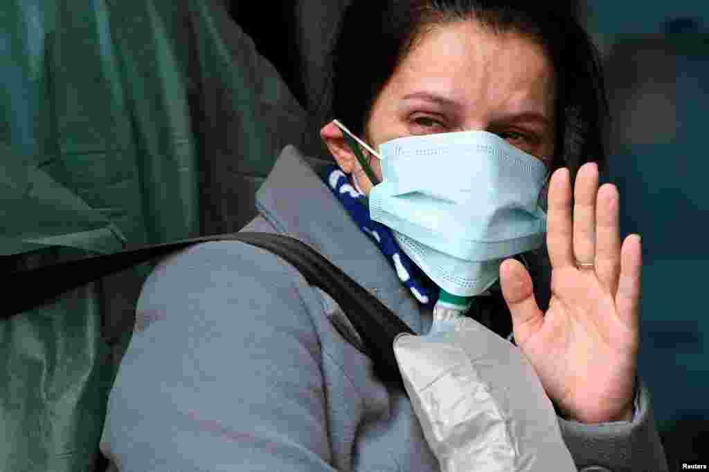 A woman possibly suffering with COVID-19 waves goodbye to her family inside an ambulance before being transported to a hospital in Arcore, near Monza, Italy.