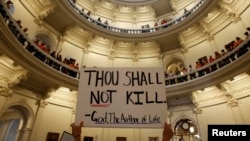 An anti-abortion protester raises a placard in the rotunda of the Texas State Capitol in Austin in this July 12, 2013, file photo.