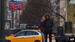 People pass by a display with exchange rates in downtown Moscow, Nov. 10, 2014.