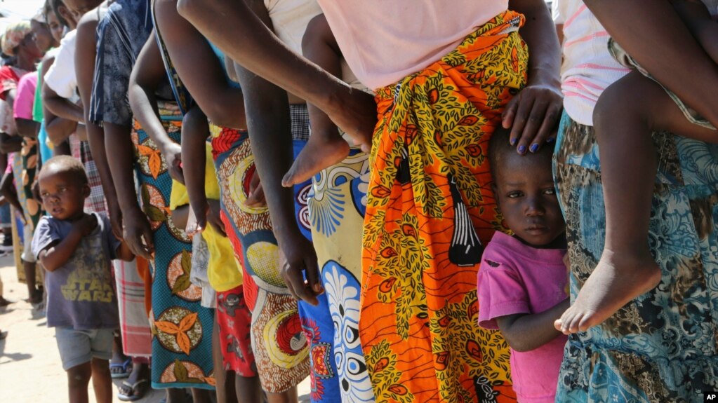 FILE - Women and children wait in a queue for oral cholera vaccinations, at a camp for displaced survivors of cyclone Idai in Beira, Mozambique, April 3, 2019.