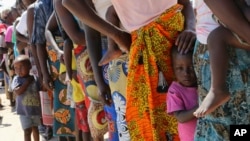 Perempuan dan anak-anak menunggu dalam antrian untuk vaksinasi kolera, di sebuah kamp untuk para pengungsi yang selamat dari topan Idai di Beira, Mozambik, Rabu, 3 April 2019. (Foto: AP)