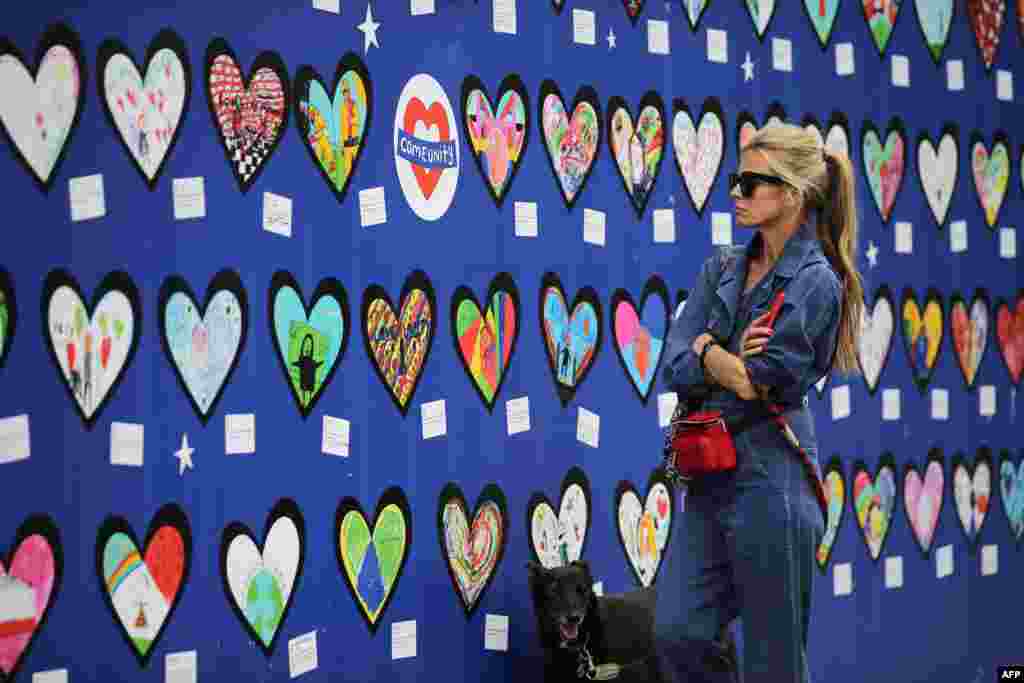 A woman looks at a wall of hearts with drawings and messages of support for the 71 people who died in the Grenfell fire, outside the Notting Hill Methodist Church in West London.