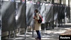 A woman looks at official European election posters outside a polling station in Paris, France, May 13, 2019.