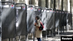 Жінка дивиться на агітаційні виборчі плакати у Парижі 