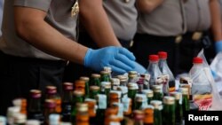 Police prepare evidence during a press conference, April 11, 2018, regarding the arrests of suspects linked to the production and sale of illegal bootleg alcohol, which claimed the lives of more than 80 people this week in Jakarta and nearby West Java province.