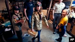 FILE - Tatum Weir, center, carries a tool box she built as her twin brother Ian, left, follows after a Cub Scout meeting in Madbury, N.H., March 1, 2018. Fifteen communities in New Hampshire are part of an "early adopter" program to allow girls to become Cub Scouts and eventually Boy Scouts. (AP Photo/Charles Krupa, File)