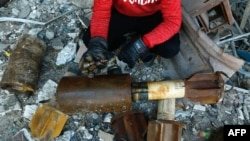 FILE - A Syrian man shows remnants of rockets reportedly fired by regime forces on the rebel-held besieged town of Douma in the eastern Ghouta region on the outskirts of the capital Damascus, Jan. 22, 2018.