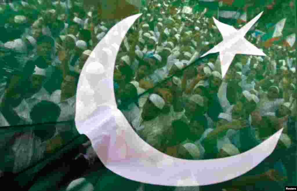 Muslim demonstrators are seen through a flag as they shout anti-U.S. slogans during a protest in Chennai, September 18, 2012.