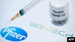 (FILES) In this file photo taken on November 23, 2020 This illustration picture taken on November 23, 2020 shows a bottle reading "Vaccine Covid-19" and a syringe next to the Pfizer and Biontech logo. - Britain on December 2, 2020 became the first country