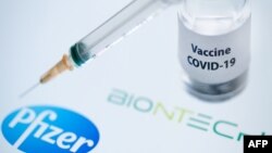 FILE PHOTO- This illustration picture taken on November 23, 2020, shows a bottle reading "Vaccine Covid-19" and a syringe next to the Pfizer and Biontech logo. (Photo by JOEL SAGET/AFP)