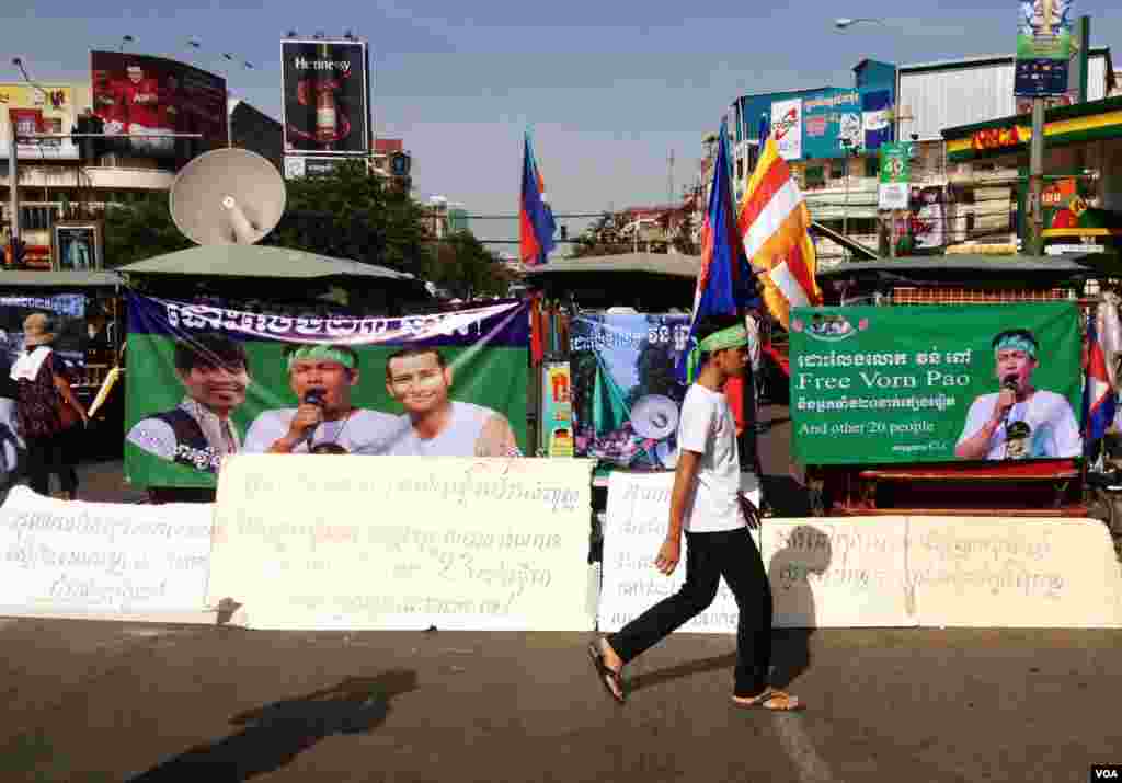 A supporter walks in front of a row of motorized rickshaws covered with banners supporting the 23 defendants in Phnom Penh, Cambodia, May 30, 2014. (Robert Carmichael/VOA)