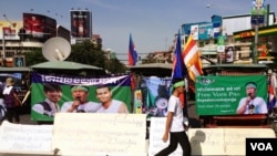 A supporter walks in front of a row of motorized rickshaws covered with banners supporting the 23 defendants in Phnom Penh, Cambodia, May 30, 2014. (Robert Carmichael/VOA)