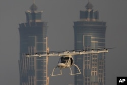 FILE - A Volocopter prototype flies in front of the two hotel towers during a test flight of pilotless taxis in Dubai, United Arab Emirates, Sept. 26, 2017.