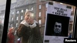 A woman takes a photo of a "Wanted" notice for fugitive Ukrainian president Viktor Yanukovych, plastered on the window of a car near Kyiv's Independence Square Feb. 24, 2014.