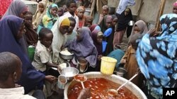 Women and children from southern Somalia receive cooked food at a distribution center in Mogadishu, Somalia, August 25, 2011