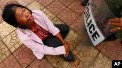 FILE - A protester cries as she confronts a line of riot police officers during a rally against land evictions near the prime minister's residence, in Phnom Penh, Cambodia, July 2, 2013.