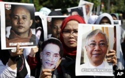 Muslim women hold posters of Wirathu, the leader of Myanmar's nationalist Buddhist monks, Myanmar's State Counsellor Aung San Suu Kyi, and President Htin Kyaw, with writings that read "The waste of humanity" during a rally against persecution of Rohingya Muslims outside Myanmar's Embassy in Jakarta, Indonesia, Sept. 7, 2017.