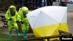 FILE - The forensic tent, covering the bench where Sergei Skripal and his daughter Yulia were found, is repositioned by officials in protective suits in the center of Salisbury, Britain, March 8, 2018.