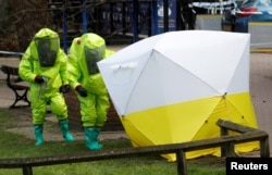 FILE - The forensic tent, covering the bench where Sergei Skripal and his daughter Yulia were found, is repositioned by officials in protective suits in the center of Salisbury, Britain, March 8, 2018.