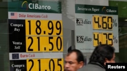 People walk past a board displaying the exchange rate for Mexican peso against the U.S. dollar and the euro in a Bank in Mexico City, Mexico, Nov. 15, 2016. 