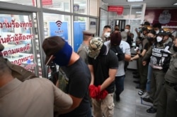 Police officers accused of complicity in the killing of a suspected drug dealer are escorted into a Nakhon Sawan police station for interrogations, in Nakhon Sawan province, Thailand, Aug. 25, 2021.