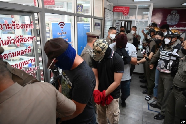 Police officers accused of complicity in the killing of a suspected drug dealer are escorted into a Nakhon Sawan police station for interrogations, in Nakhon Sawan province, Thailand, Aug. 25, 2021.