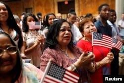 New citizens stand during a U.S. Citizenship and Immigration Services (USCIS) naturalization ceremony at the New York Public Library in Manhattan, New York, July 3, 2018.