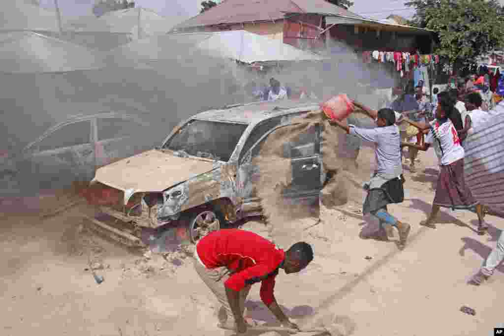 Somalis pour sand to smother a car fire after a car bomb in Mogadishu, Somalia. At least one person was killed and others injured and nobody has claimed responsibility for the blast.