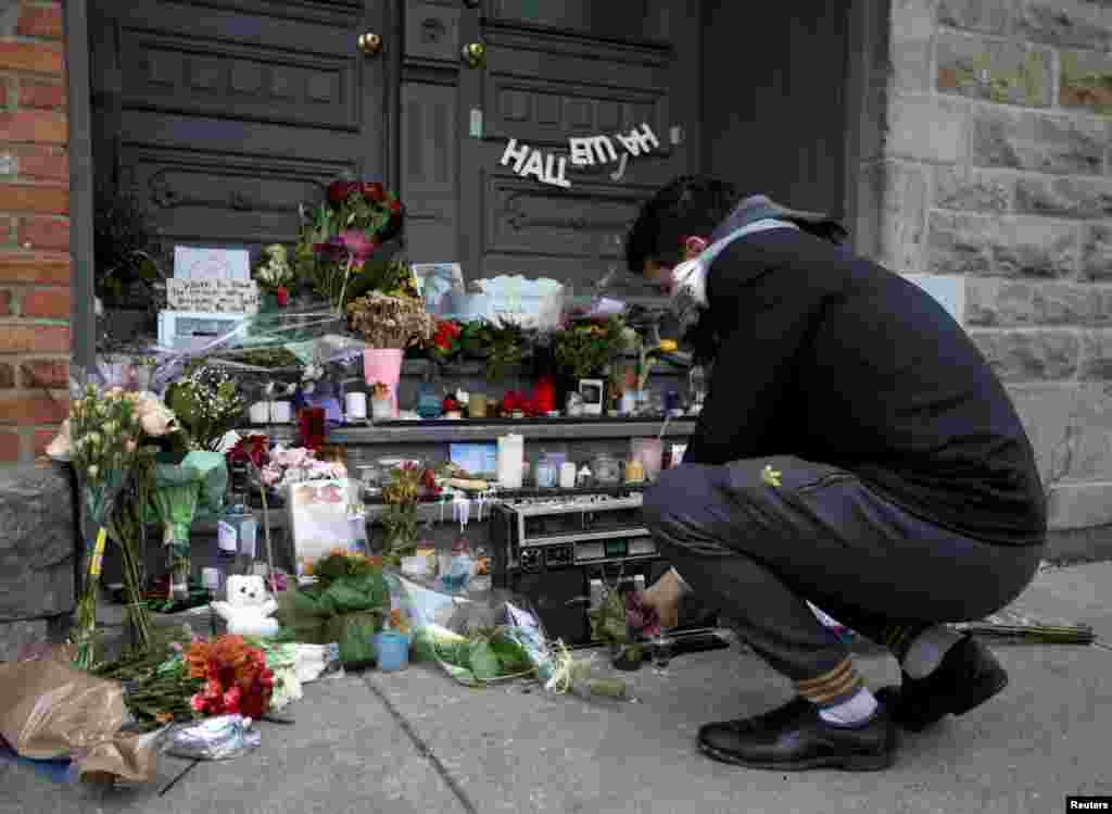 A mourners plays a cassette of music from Canadian singer-songwriter Leonard Cohen as tributes are left on the steps of the home he owns in Montreal, Nov. 11, 2016. 