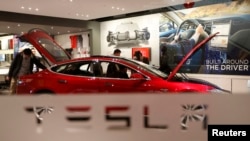 FILE - A man looks around Tesla Motors' Model S P85 at its showroom in Beijing, China.