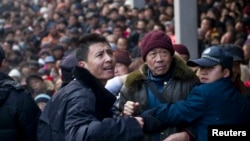 FILE - Security personnel try to control the crowd as locals visit the Lingyin Temple during the Laba Festival in Hangzhou, Zhejiang province January 19, 2013. 