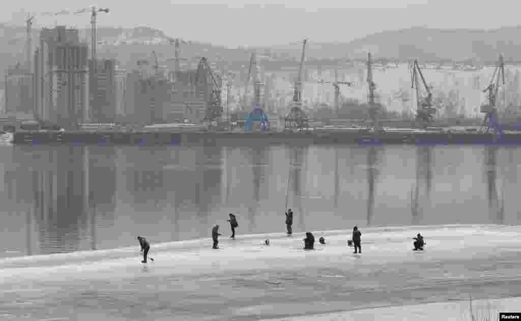 Men fish on the ice-covered Yenisei River in Krasnoyarsk, Russia.