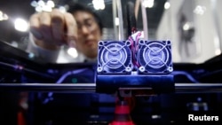 FILE - A staff member of Nihonbinary demonstrates their 3D printer MakerBot Replicator 2X as it prints an Acrylonitrile butadiene styrene pylon during the International Robot Exhibition 2013 in Tokyo, Nov. 8, 2013. 