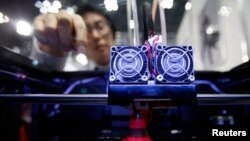 FILE - A staff member of Nihonbinary demonstrates their 3D printer MakerBot Replicator 2X as it prints an Acrylonitrile butadiene styrene pylon during the International Robot Exhibition 2013 in Tokyo, Nov. 8, 2013. 