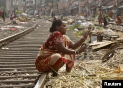 A woman peels sugarcanes on a railway track to sell it to sugarcane juice vendors at a slum area in Kolkata, India May 10, 2015.