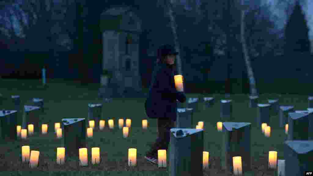 Un enfant apporte une bougie à un cimetière juif, à l&#39;ancien camp de concentration nazi en Terezin Terezin (Theresiendstadt) lors de la cérémonie pour marquer le 70e anniversaire de la libération de l&#39;ancien camp de concentration nazi d&#39;Auschwitz-Birkenau à Oswiecim, Pologne.