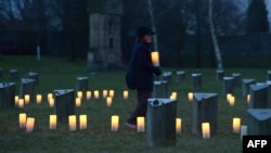 A Child brings a candle to at a Jewish cemetery at the former Terezin Nazi concentration camp on January 27, 2015, in Terezin (Theresiendstadt ) during the ceremony to mark the 70th anniversary of the liberation of the former Nazi concentration camp Ausch