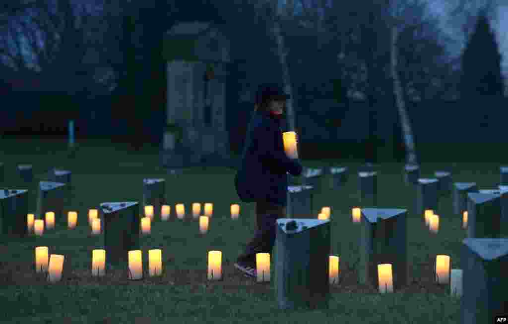 A child brings a candle to a Jewish cemetery at the former Terezin Nazi concentration camp in Terezin (Theresiendstadt ) during the ceremony to mark the 70th anniversary of the liberation of the former Nazi concentration camp Auschwitz-Birkenau in Oswiecim, Poland.