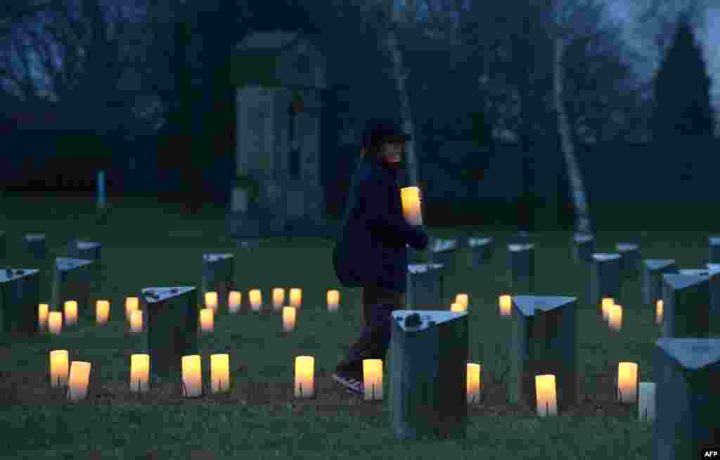 Seorang anak membawa lilin ke tempat pemakaman Yahudi di bekas kamp konsentrasi Nazi, Terezin di Ceko, dalam upacara yang menandai 70 tahun pembebasan penghuni kamp konsentrasi Nazi di Auschwitz (27/1). (​AFP/Michal Cizek)