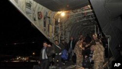 In this photo released by Britain's Ministry of Defense, civilians disembark from one of two Royal Air Force C130 Hercules that evacuated more than 150 civilians from desert locations south of Benghazi, at Malta's international airport, February 27, 2011