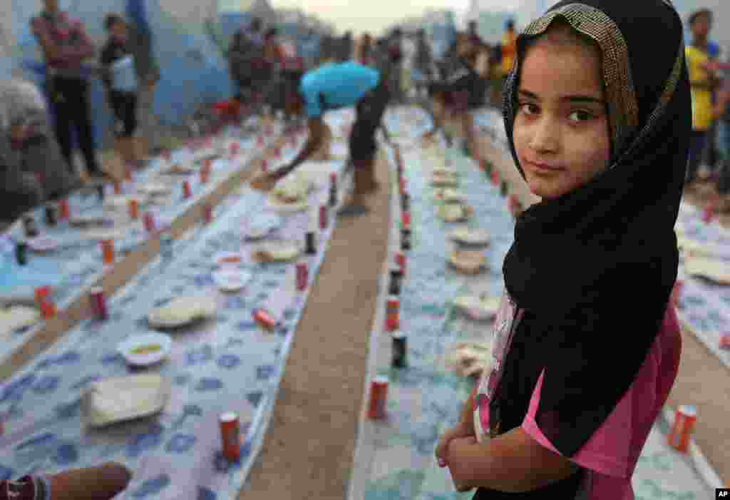 A displaced Iraqi girl waits with others for a communal meal to break their fast at sunset during the first day of the Islamic holy month of Ramadan, at an encampment for displaced Iraqis who fled from their homes, in the Khazer area outside Irbil, northern Iraq, June 29, 2014.