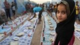 A displaced Iraqi girl waits with others for a communal meal to break their fast at sunset during the first day of the Islamic holy month of Ramadan, at an encampment for displaced Iraqis who fled from their homes, in the Khazer area outside Irbil, northern Iraq, June 29, 2014.
