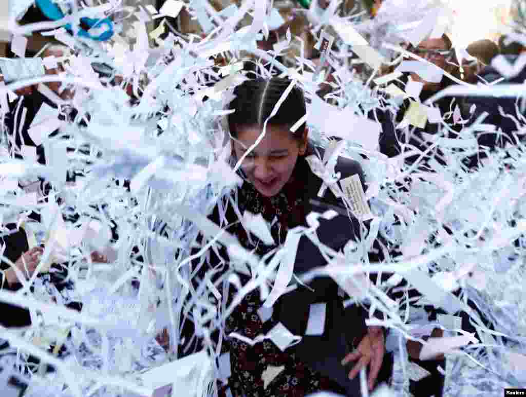 A woman reacts as she is hit by a bale of confetti during a band march at the feast marking the shipwreck in 60 A.D. of Saint Paul, Malta&#39;s patron saint, in Valletta, Malta, Jan. 27, 2018.