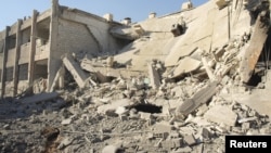 Các tòa nhà bị hư hại, theo lời các nhà hoạt động, vì các cuộc oanh kích của máy bay của lực lượng không quân trung thành với Tổng thống al-Assad